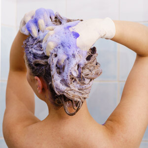 Woman applying violet shampoo on her hair
