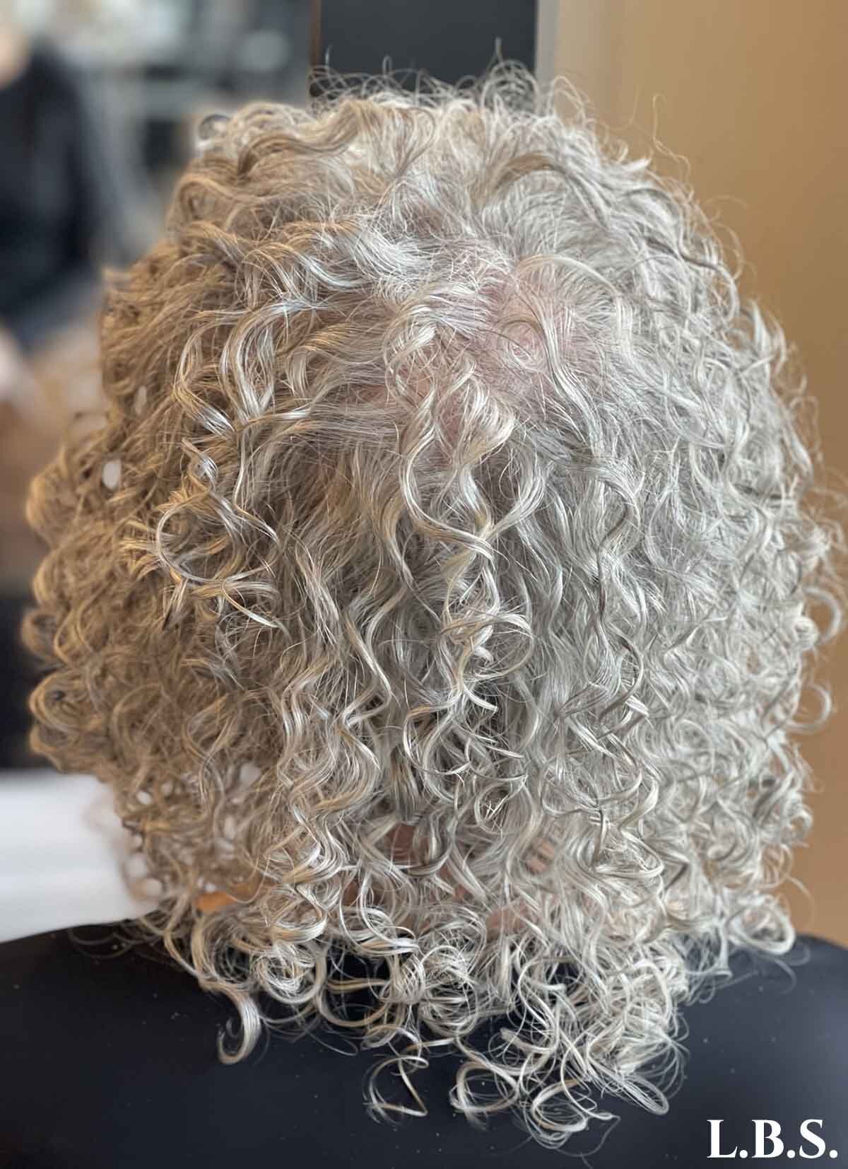 Woman facing away with short curly silver hair.