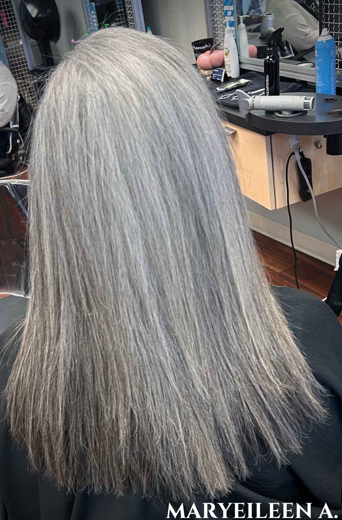 Woman facing away from camera with long straight silver hair.