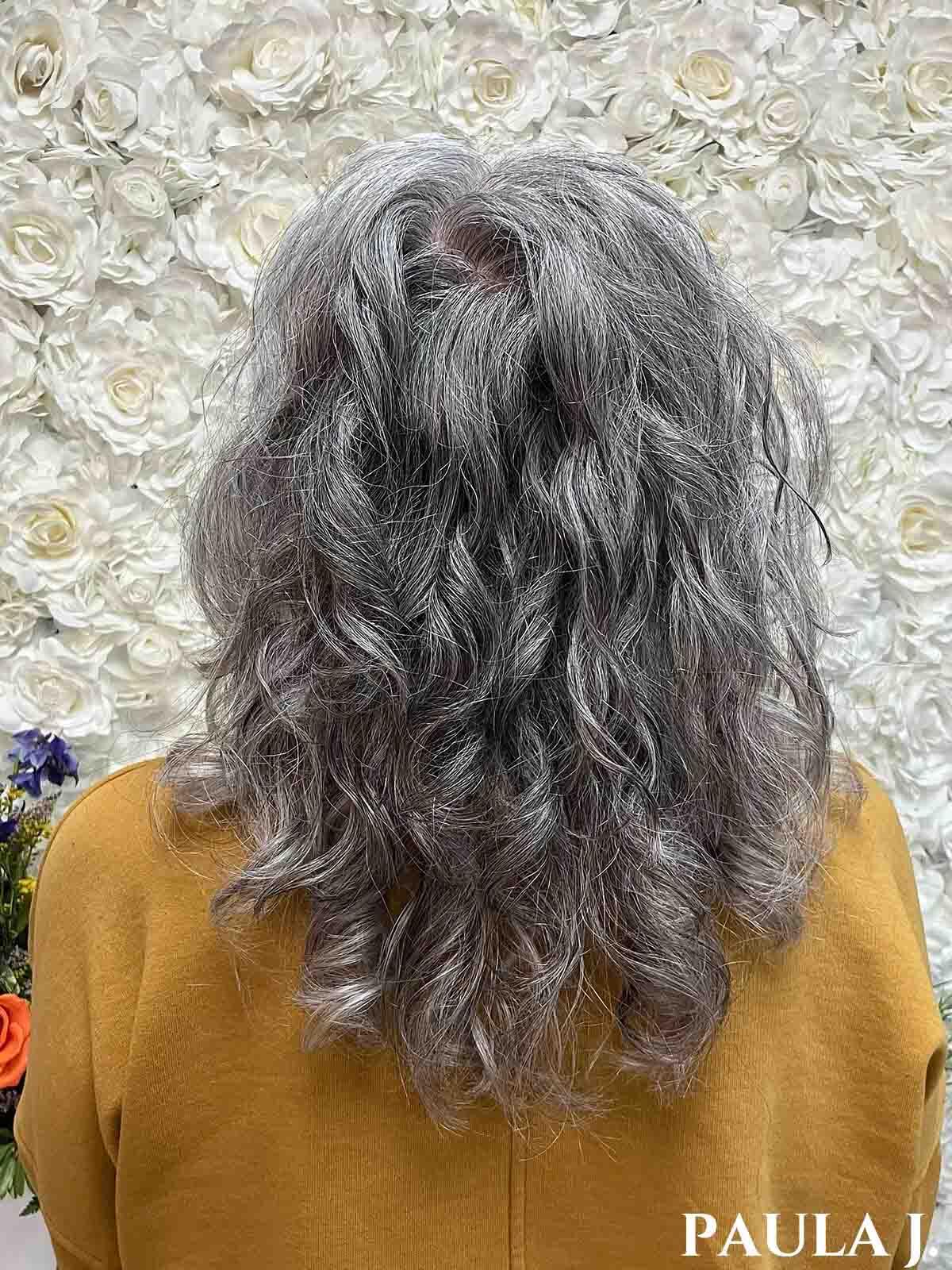 Woman facing away with long curly silver hair.