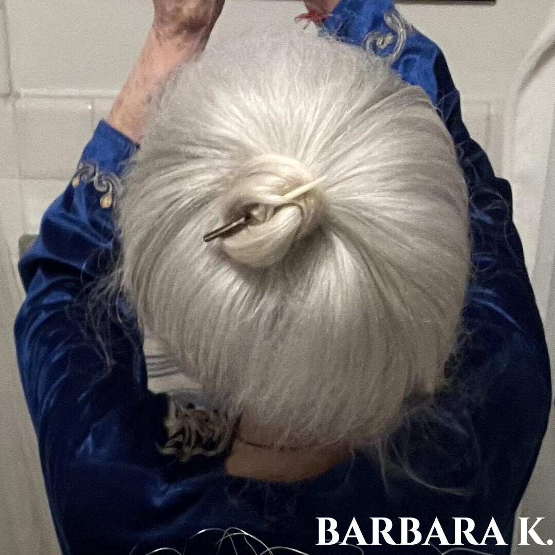 Woman facing away with long whit hair in a bun.