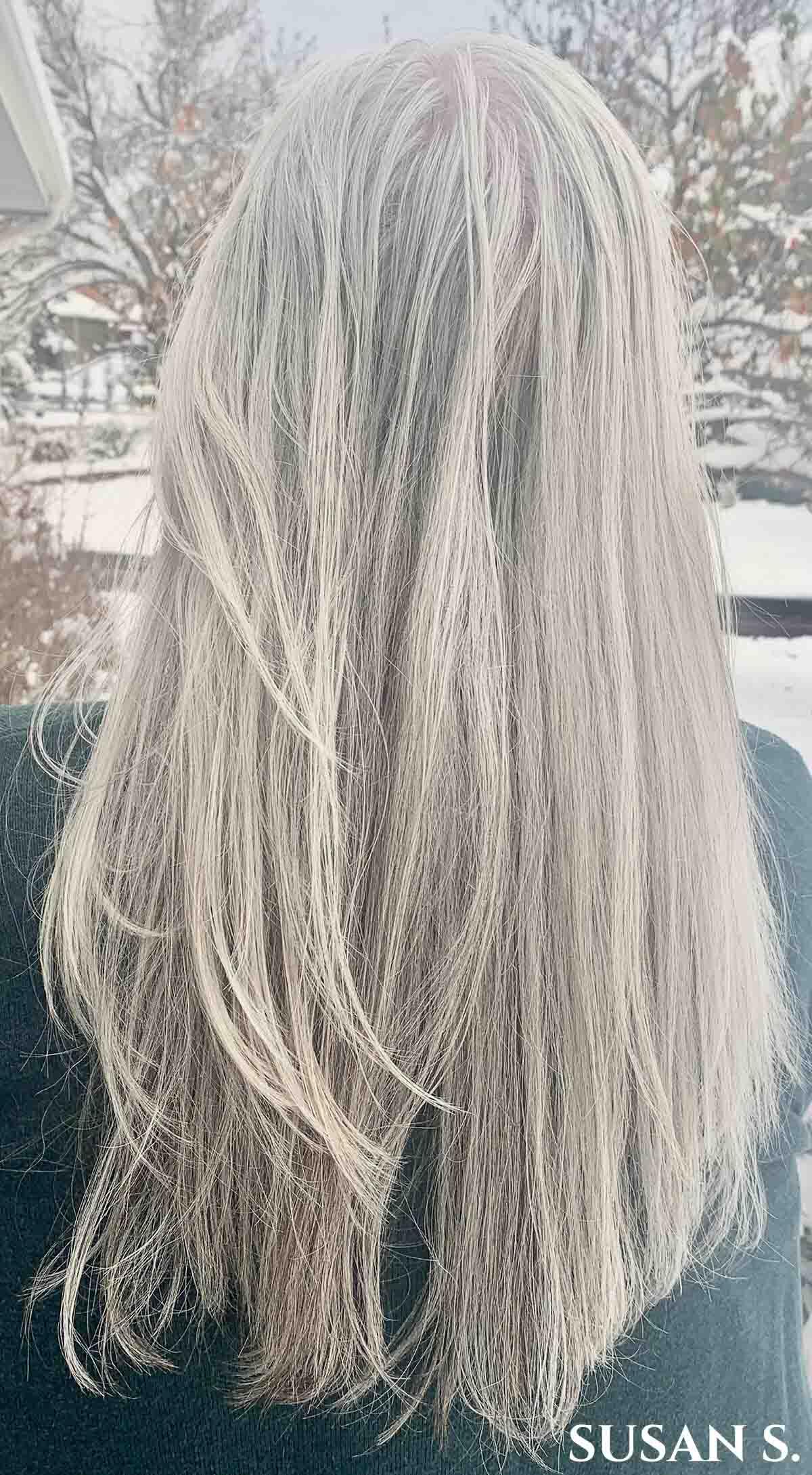 Woman facing away with mid back length straight white hair.