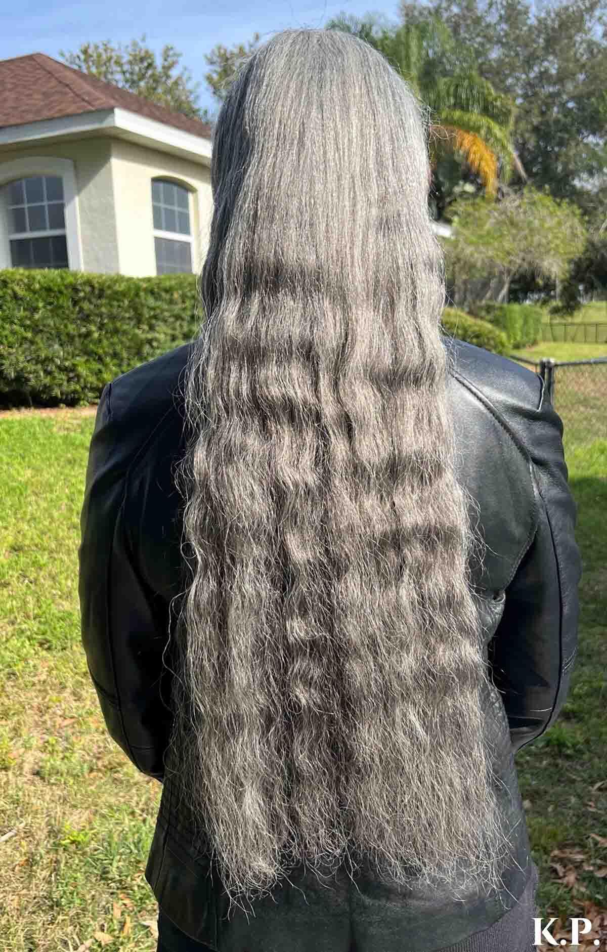 Woman facing away with really long wavy silver hair.